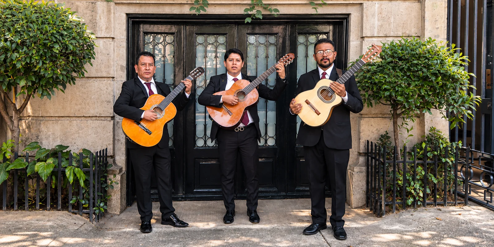 Tres integrantes de un trío musical con guitarras en una presentación formal